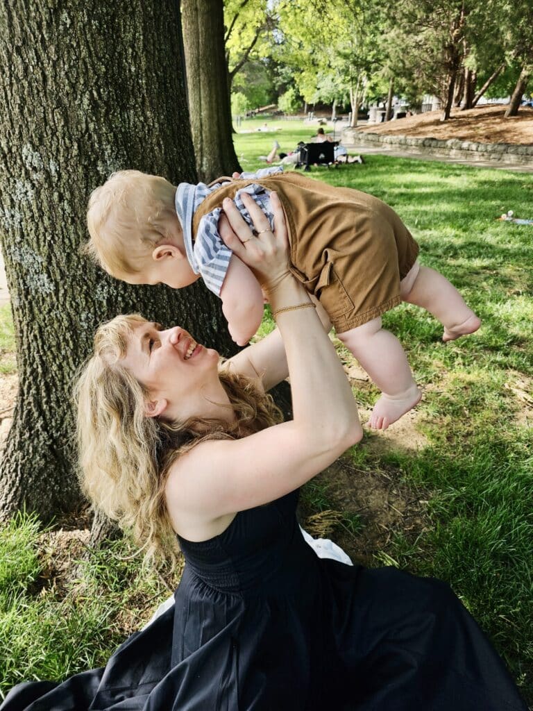 photo of a young mother, lifting her son in a parklike setting