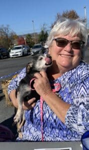 photo of a woman wearing sunglasses, holding a small dog