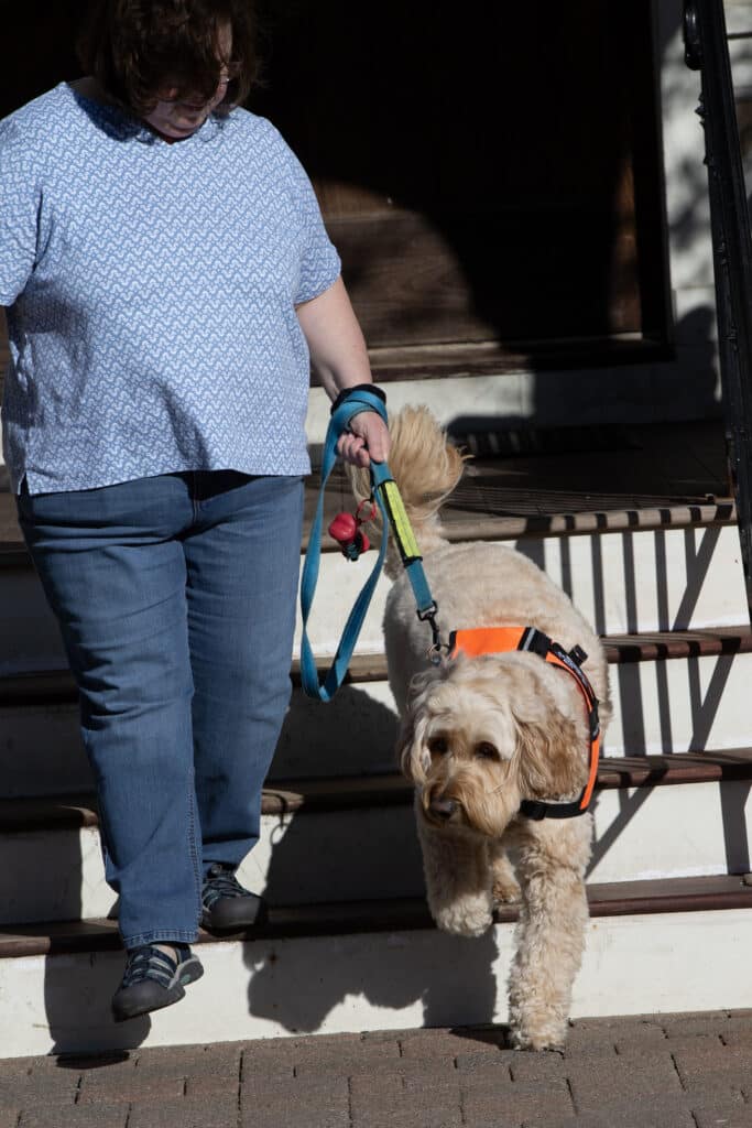 photo of a woman descending stairs with a service dog
