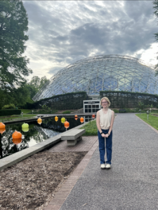 smiling woman standing on a path leading to a large geodesic dome