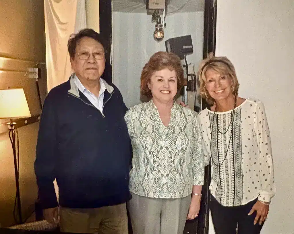 a smiling man and two women posing for a group photo