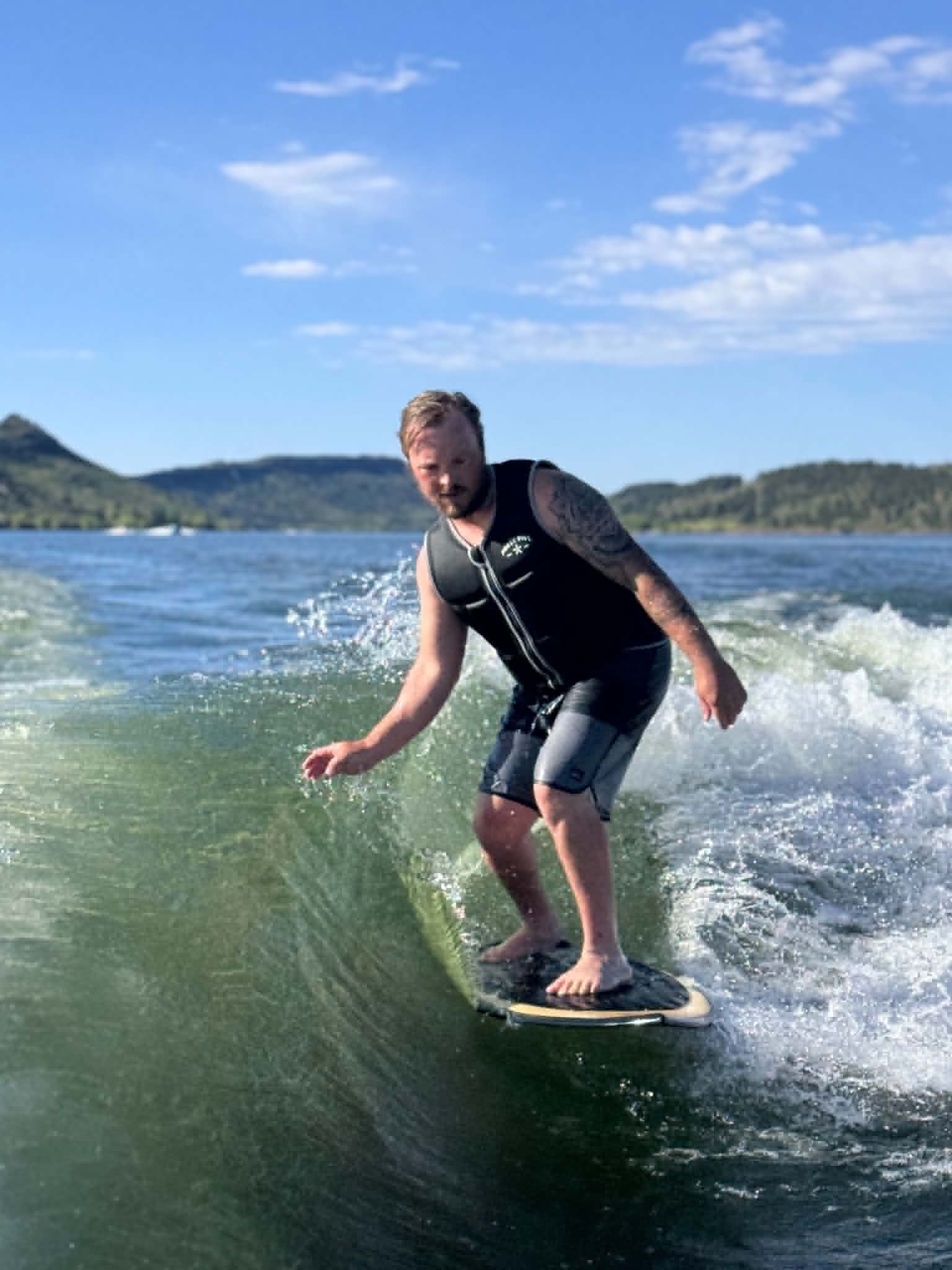 a man wakesurfing on a lake with low mountains in the background